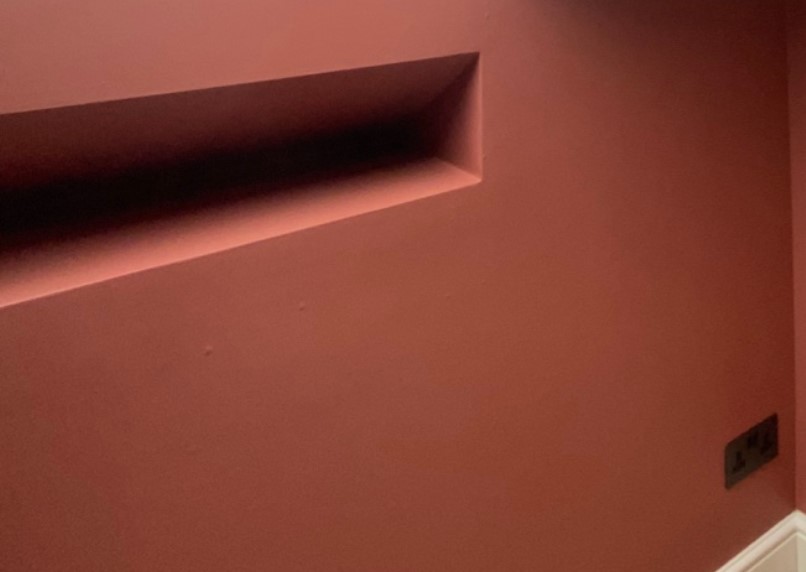 Close view of a terracotta corner with a dimmer switch and socket painted to match